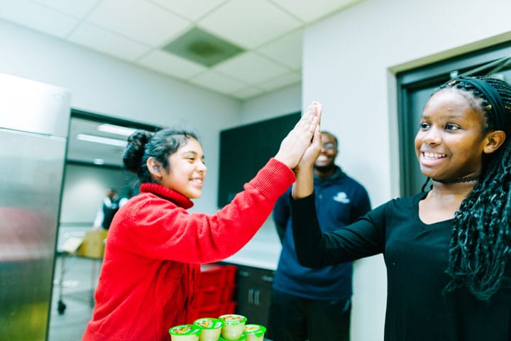two young female boys & girls clubs members give each other a high five