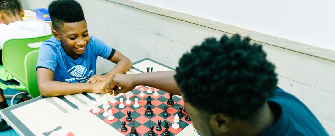 Two young boys & girls clubs members playing chess