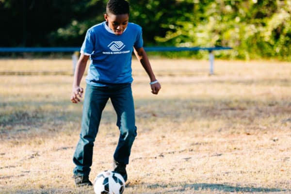 A young Boys & Girls Clubs member playing with a soccer ball