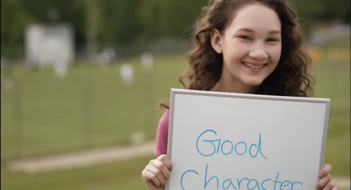 a young girl holding a sign that says "good character"